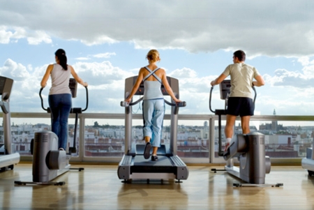 Rear view of People using exercise equipment in front of a window