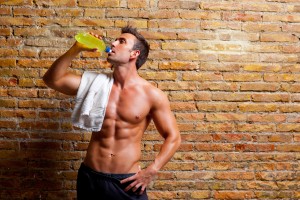 muscle shaped man at gym relaxed drinking